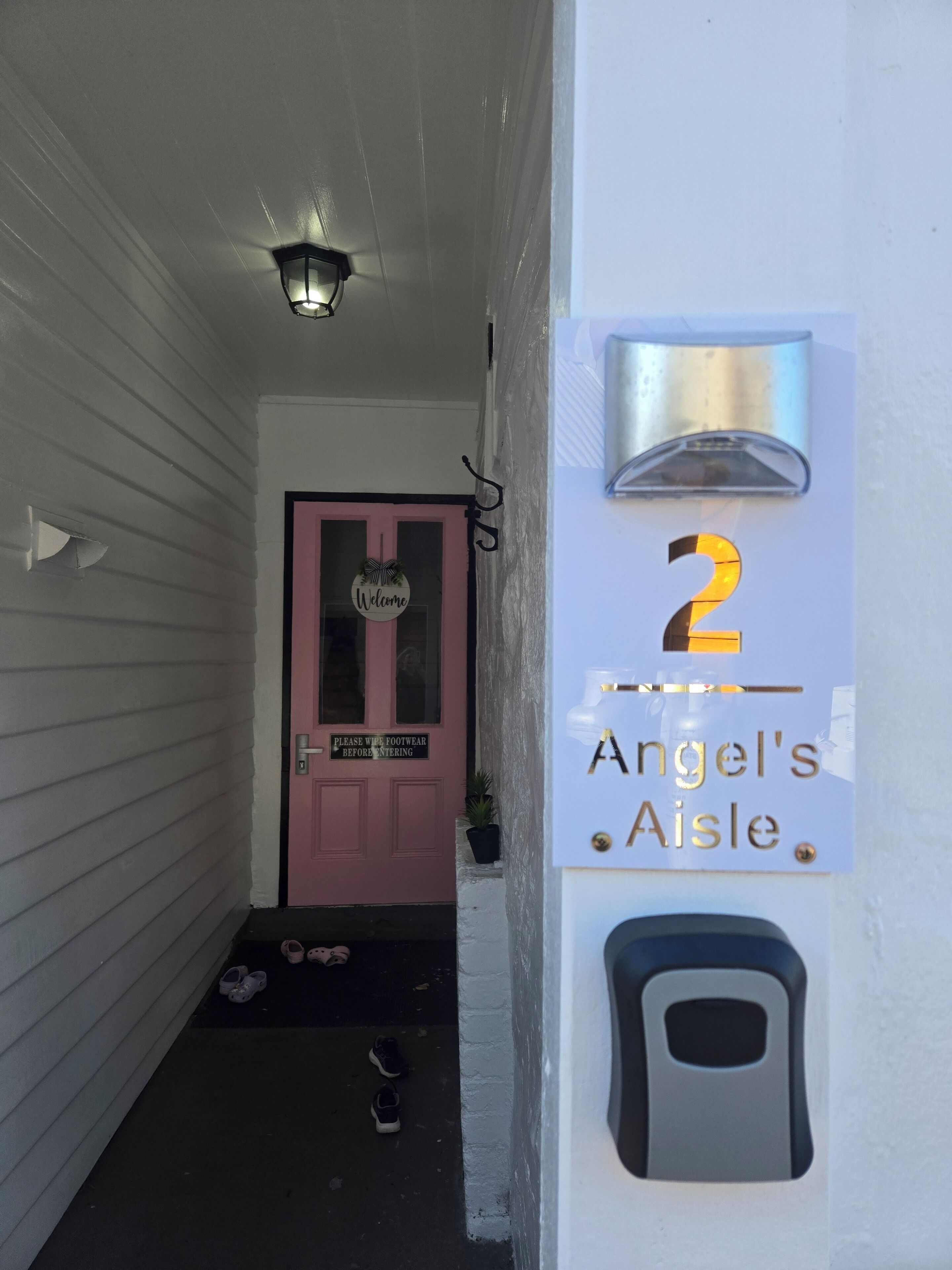 Le numéro de maison « 2 » et une enseigne « Angel’s Aisle » sont peints sur un mur blanc.