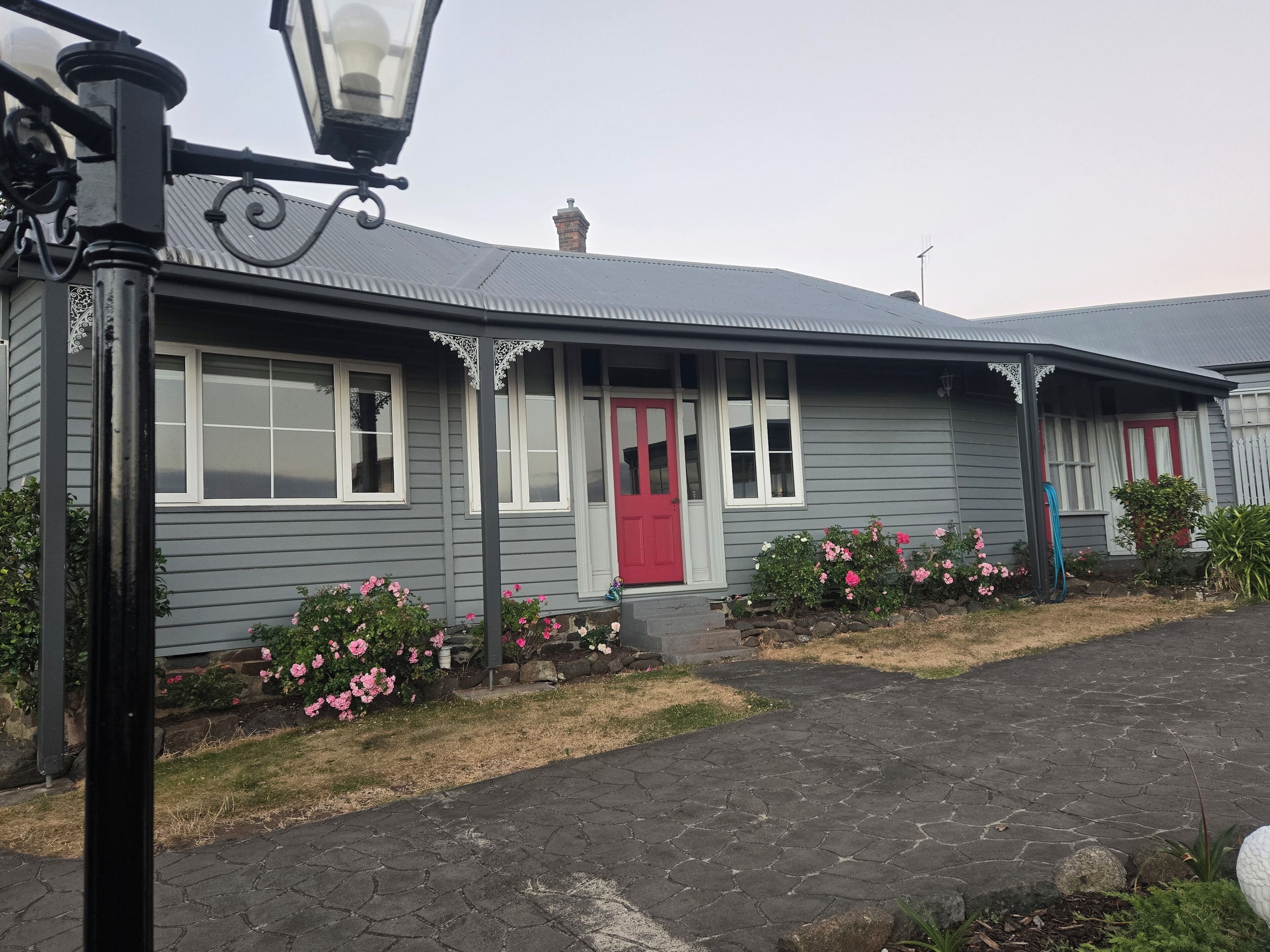 A house with a red door, white windows, and a grey exterior.