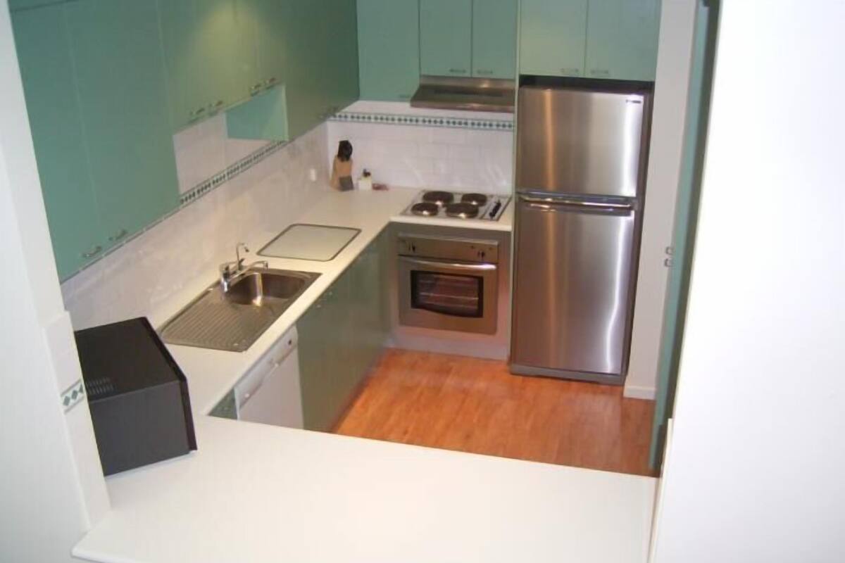 A compact kitchen with a sink, stove, oven, and refrigerator.