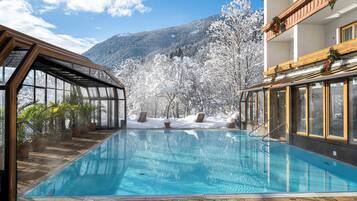 Una piscina con vista a árboles nevados y montañas al fondo.