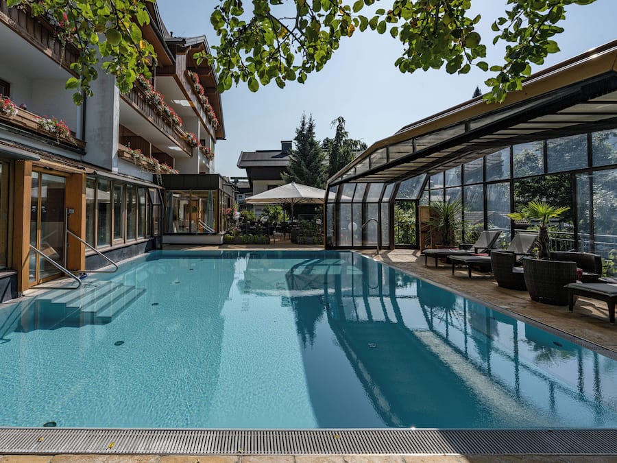 Ein Swimmingpool mit klarem, blauem Wasser, umgeben von einer überdachten Terrasse mit Sitzgelegenheiten im Freien.