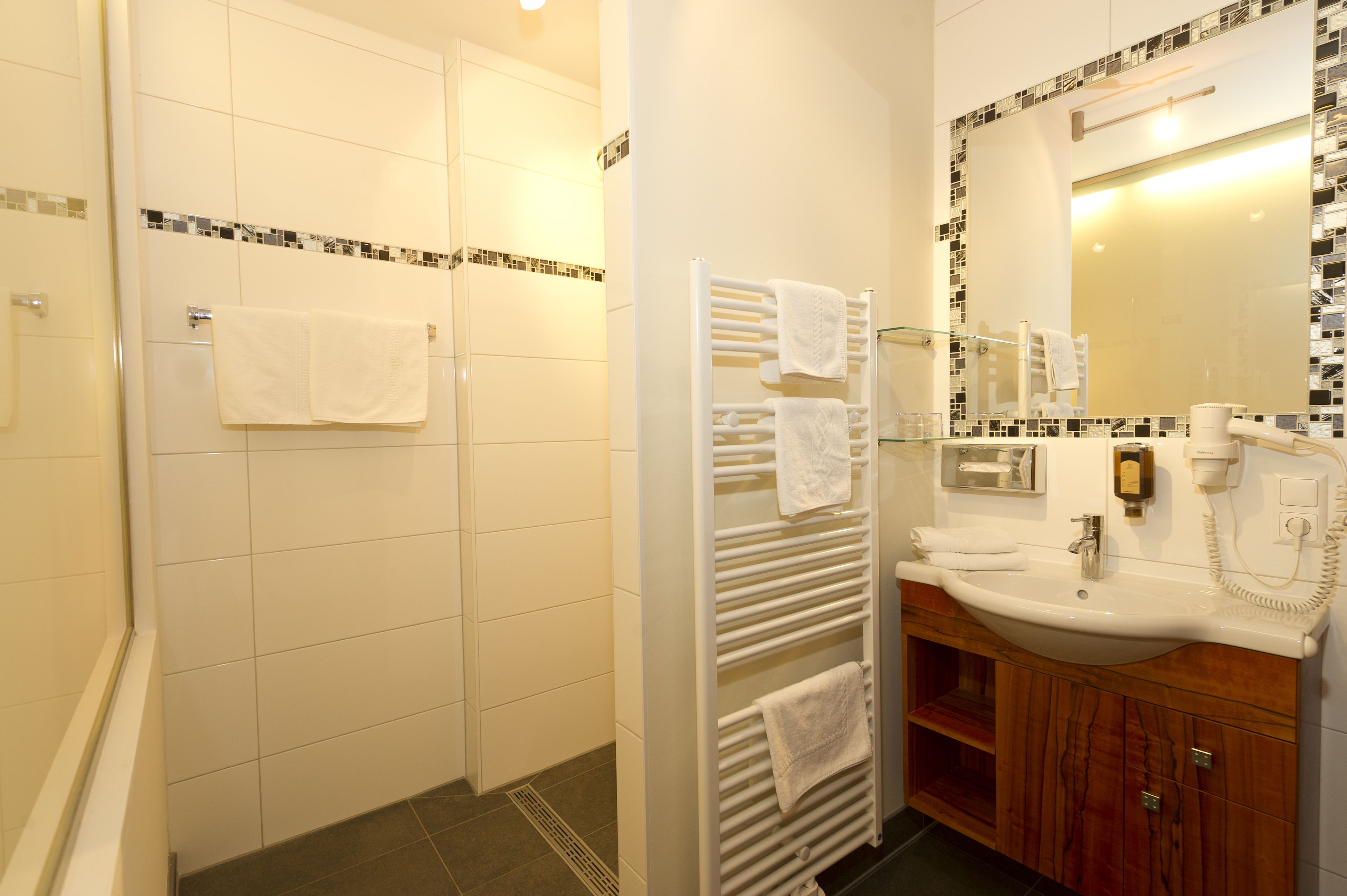 A bathroom with a shower, a sink, and a mirror.