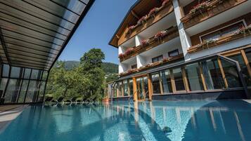 Ein Hotel mit Schwimmbad, Holzbalkonen mit Blumenkästen und großen Fenstern.