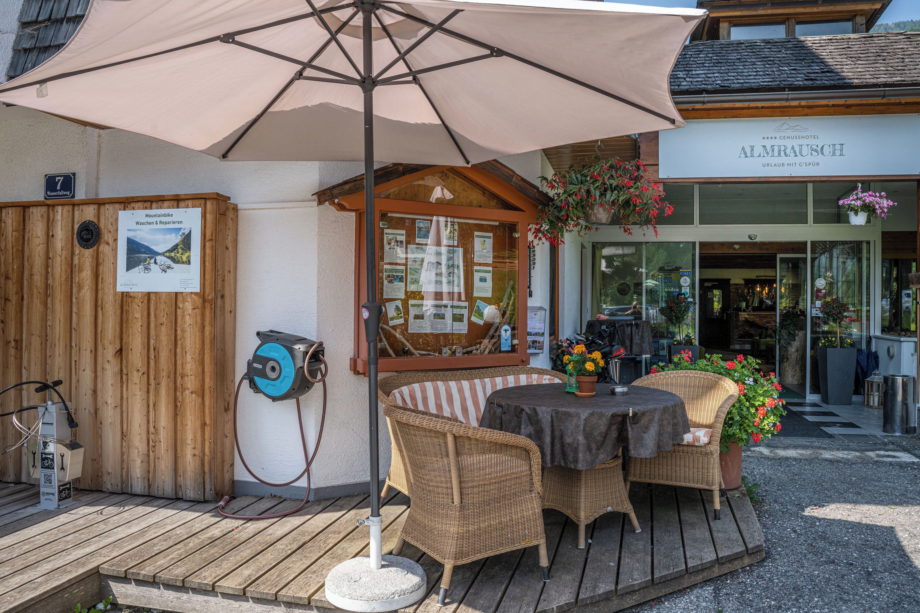 A wooden deck with wicker furniture, an umbrella, and a sign for a mountain bike rental service.