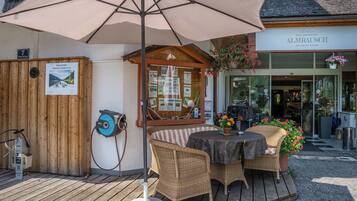A wooden deck with wicker furniture, an umbrella, and a sign for a mountain bike rental service.