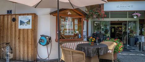 A wooden deck with wicker furniture, an umbrella, and a sign for a mountain bike rental service.