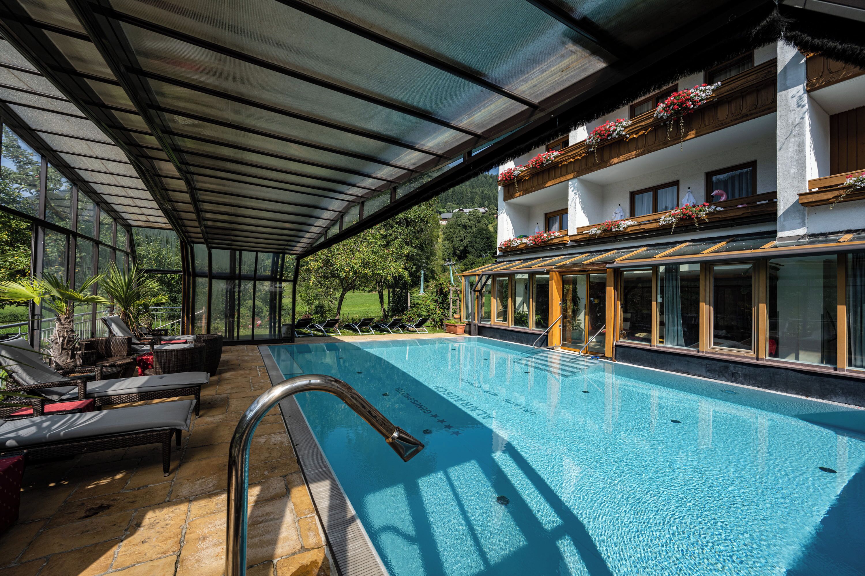Una piscina con sillones de descanso y un área cubierta.