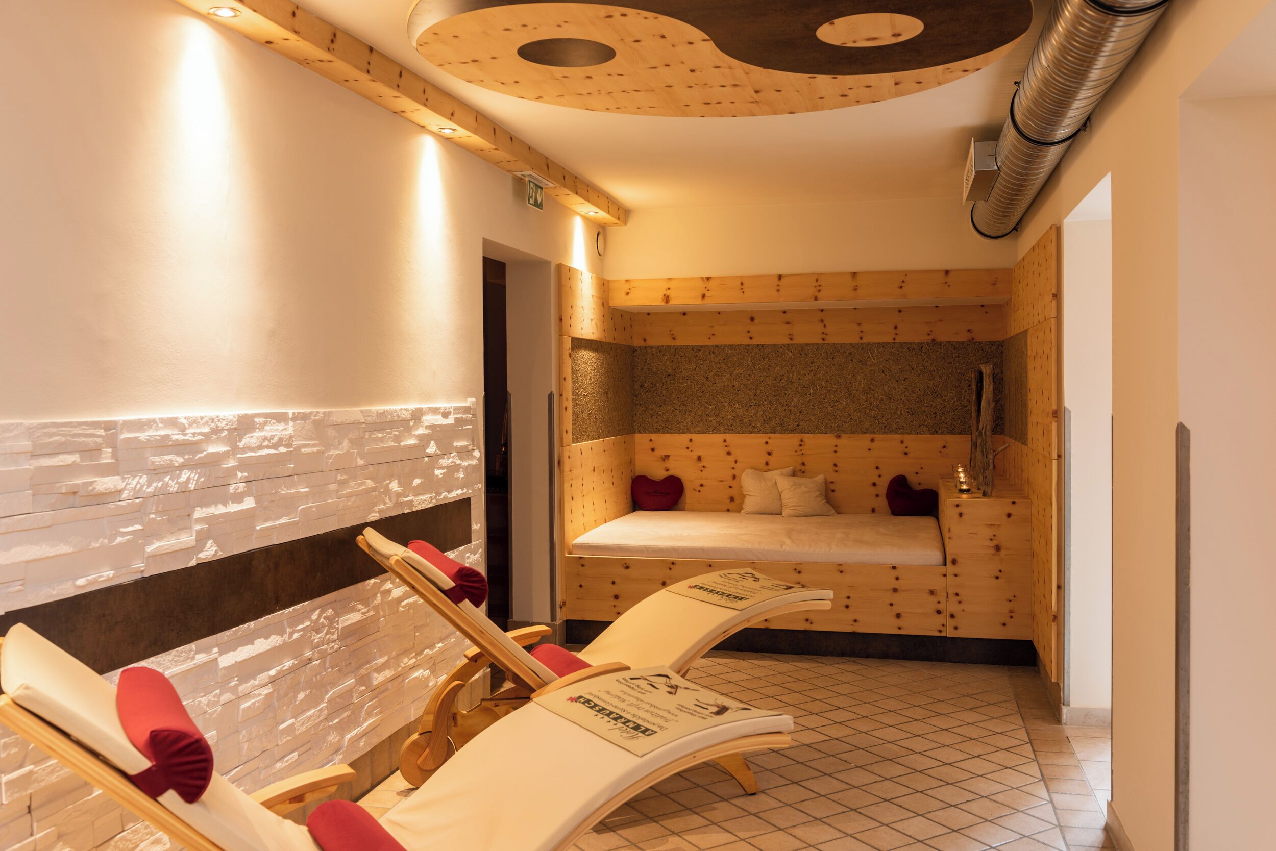 A spa room with wooden paneling, a bed, and two lounge chairs.