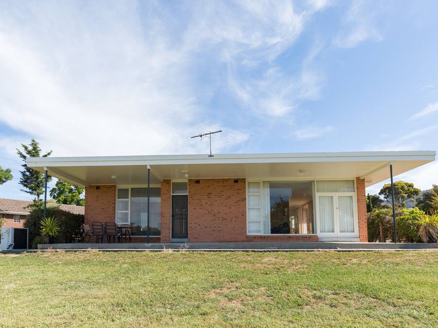 A modern two-story house with a flat roof, a covered porch, and a brick exterior.