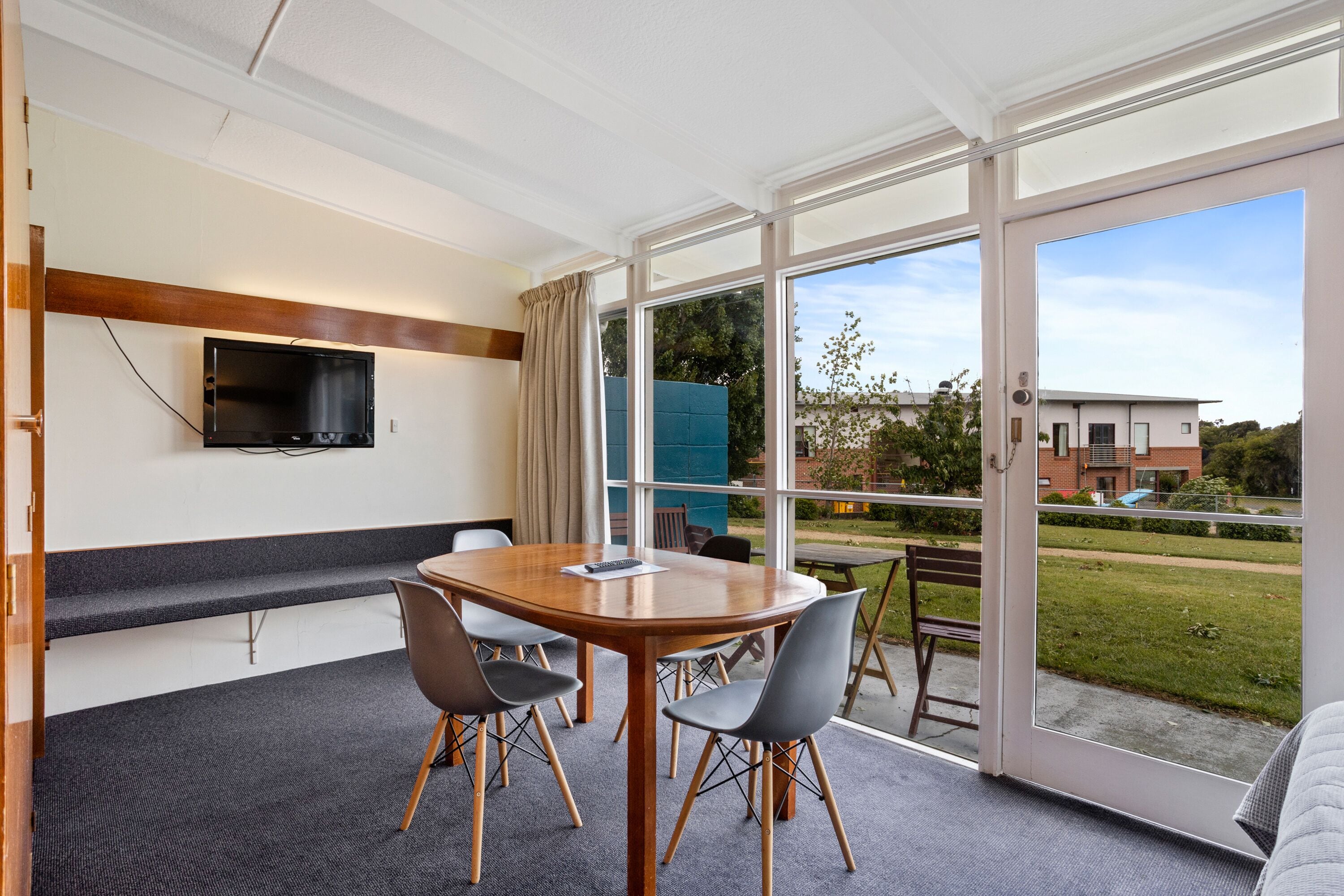 A conference room with a large table, chairs, a TV, and a view of the outdoors.
