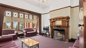 A cozy living room with a fireplace, comfortable seating, and large windows with decorative glass.