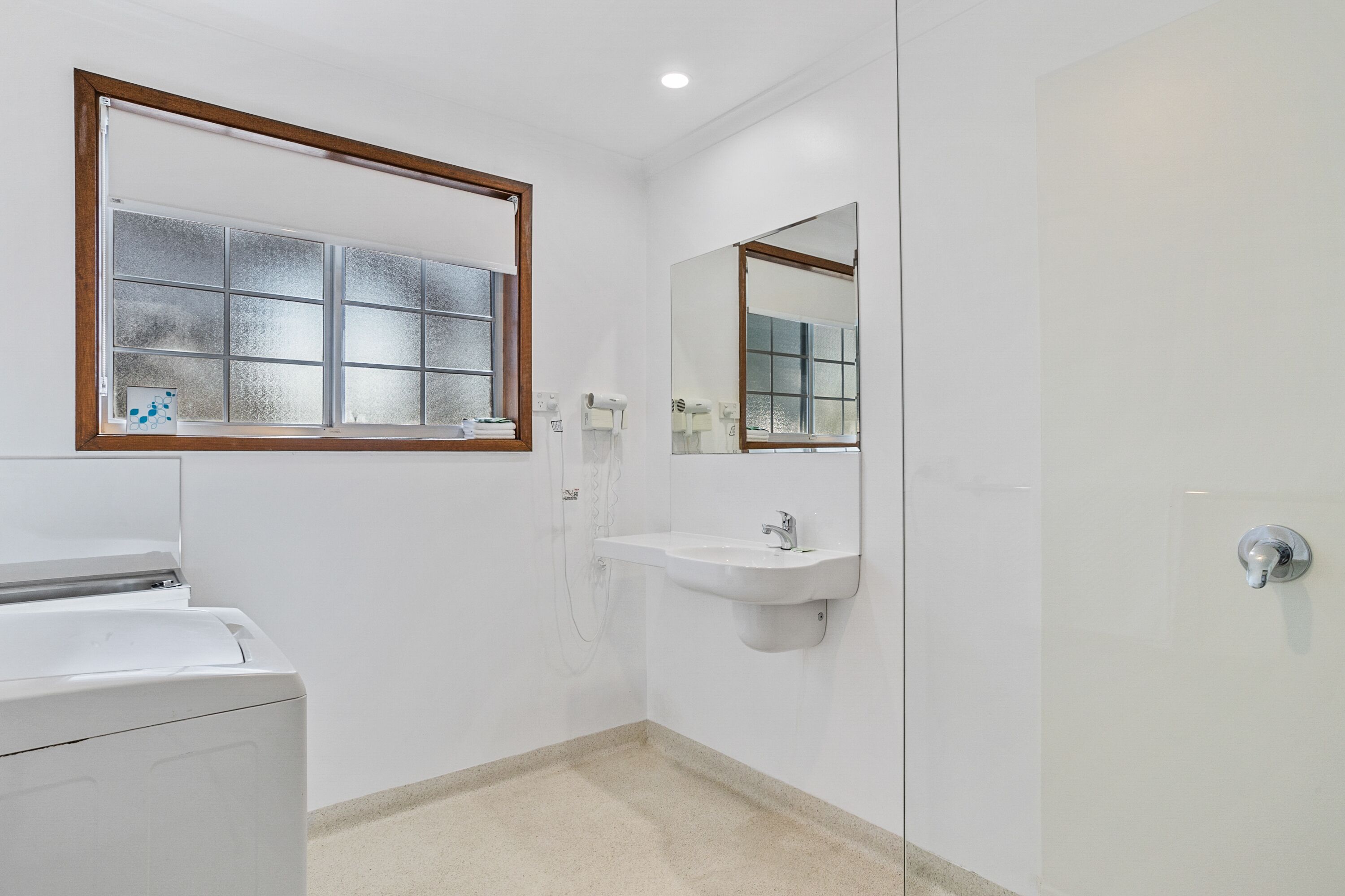 A bathroom with a glass shower enclosure, a white sink, and a mirror above the sink.