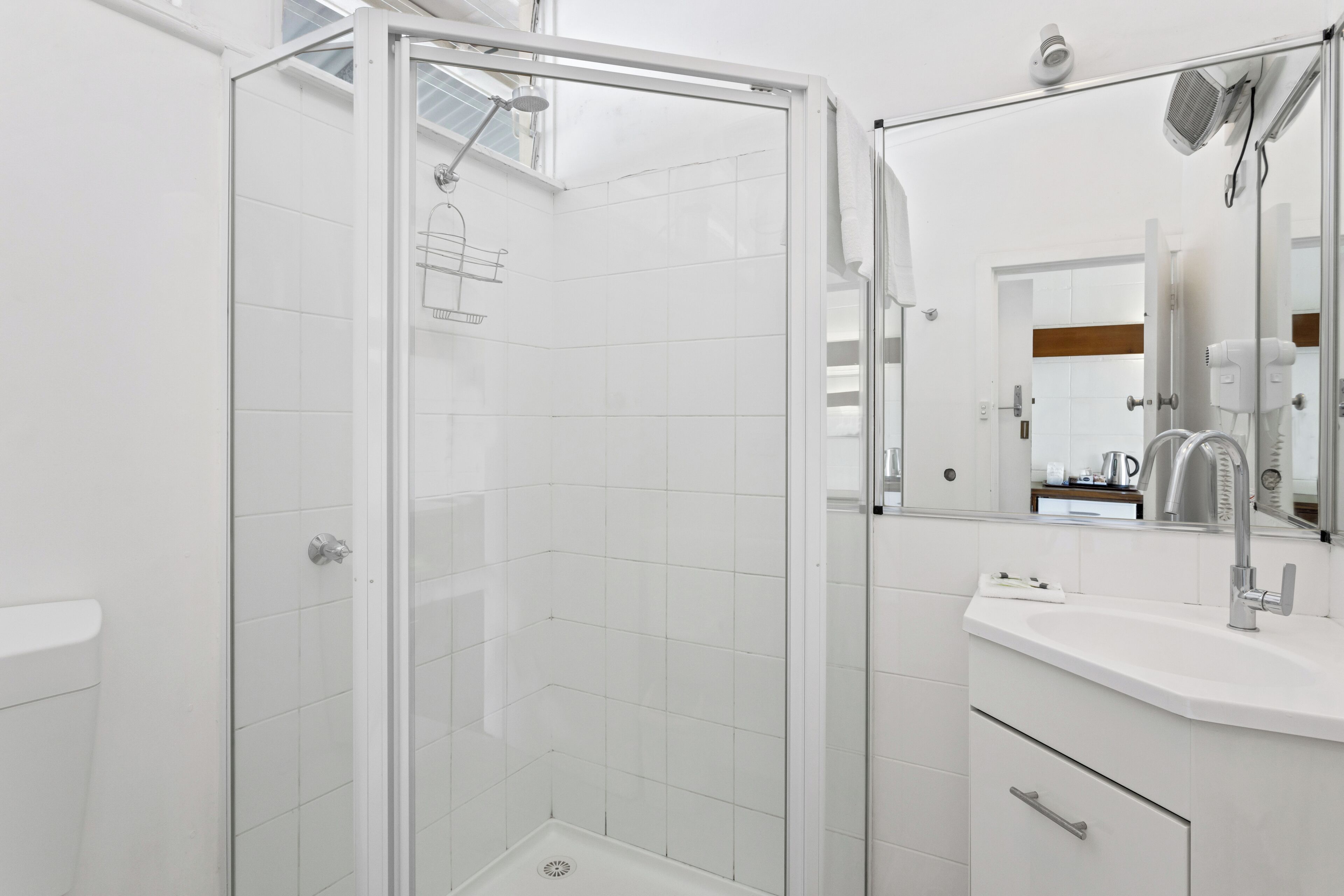 A modern bathroom with a glass-enclosed shower, a white sink, and a mirror above it.