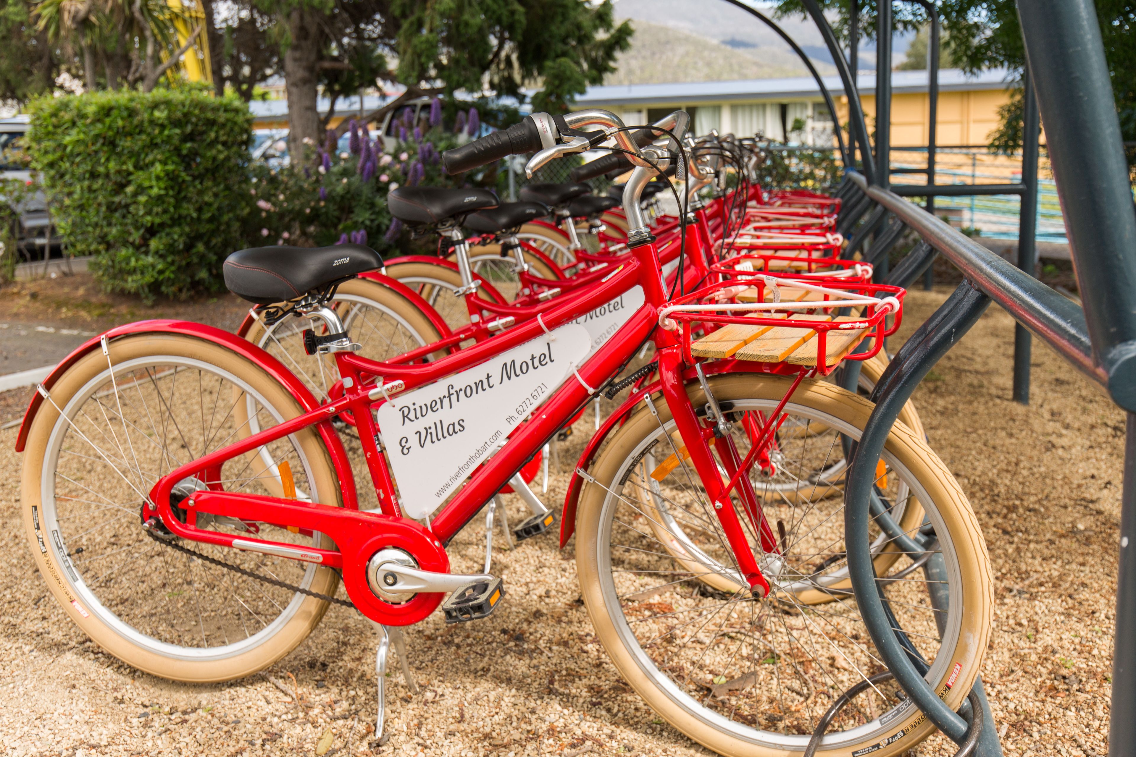 A row of red bicycles with a sign that reads "Riverfront Motel & Villas."