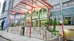 Ingresso di un hotel con una tettoia in vetro, scale che conducono all'ingresso e una segnaletica con il nome e l'indirizzo dell'hotel.