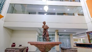 Una hall con fontana centrale, zone salotto e soffitto alto con ringhiere in vetro.