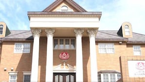 A large building with a symmetrical facade, featuring a central entrance with columns, and a sign above the entrance. - Petit Hotel Corinthian (Rebun)