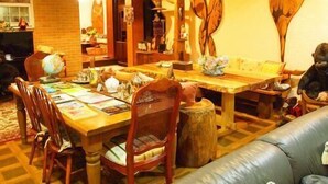 A cozy dining area with a wooden table and chairs, a sofa, and decorative wall art. - Petit Hotel Corinthian (Rebun)