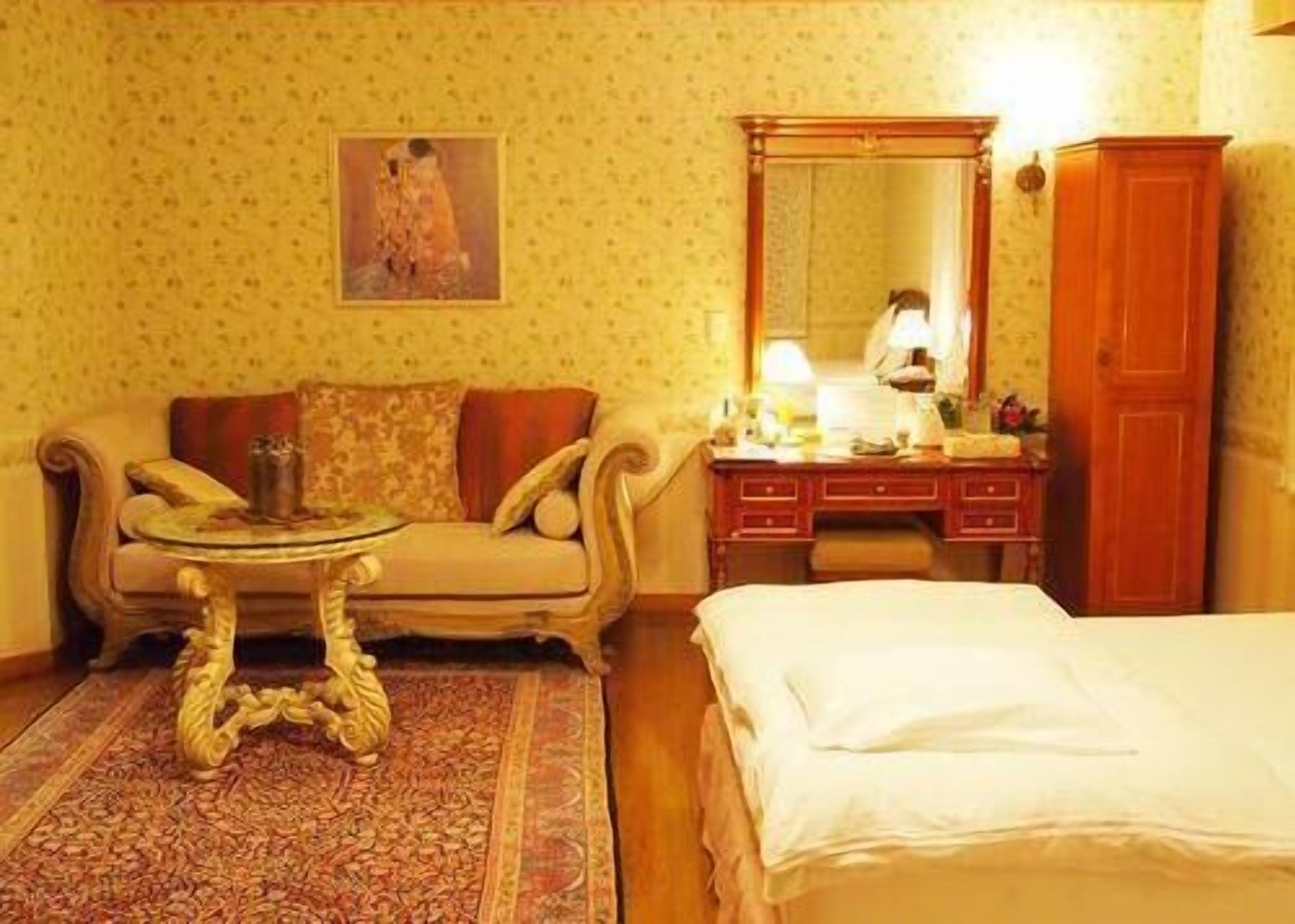 Een kamer met een bed, een slaapbank, een tafeltje, een dressoir en een spiegel.