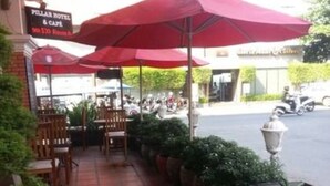 An outdoor seating area with red umbrellas, potted plants, and a sign for the Peller Hotel & Casino. - Pillar Hotel (Phnom Penh)