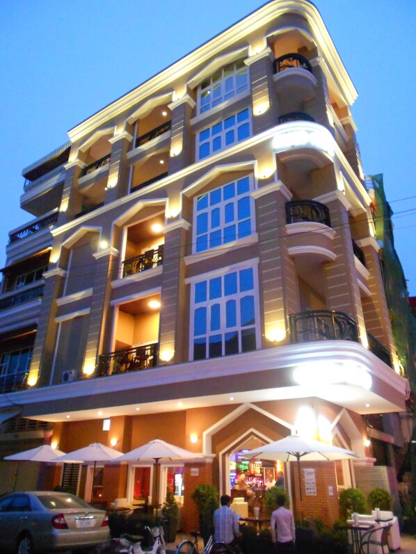 Un hotel de varios pisos con balcones, zona de estar al aire libre y bar.
