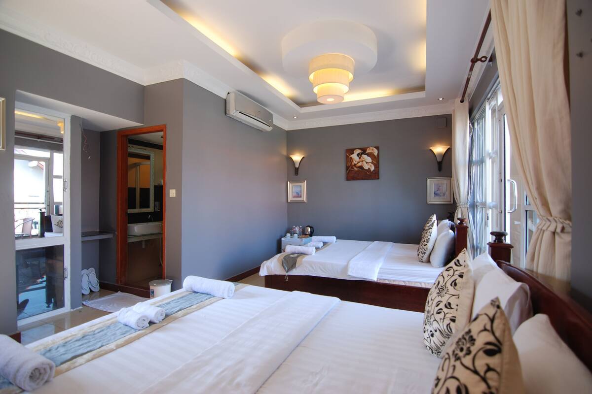 A hotel room with two beds, a bathroom, and a view of the sea.