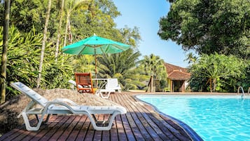 Una piscina al aire libre, sombrillas, tumbonas