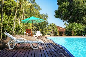 Una piscina al aire libre, sombrillas, sillones reclinables de piscina