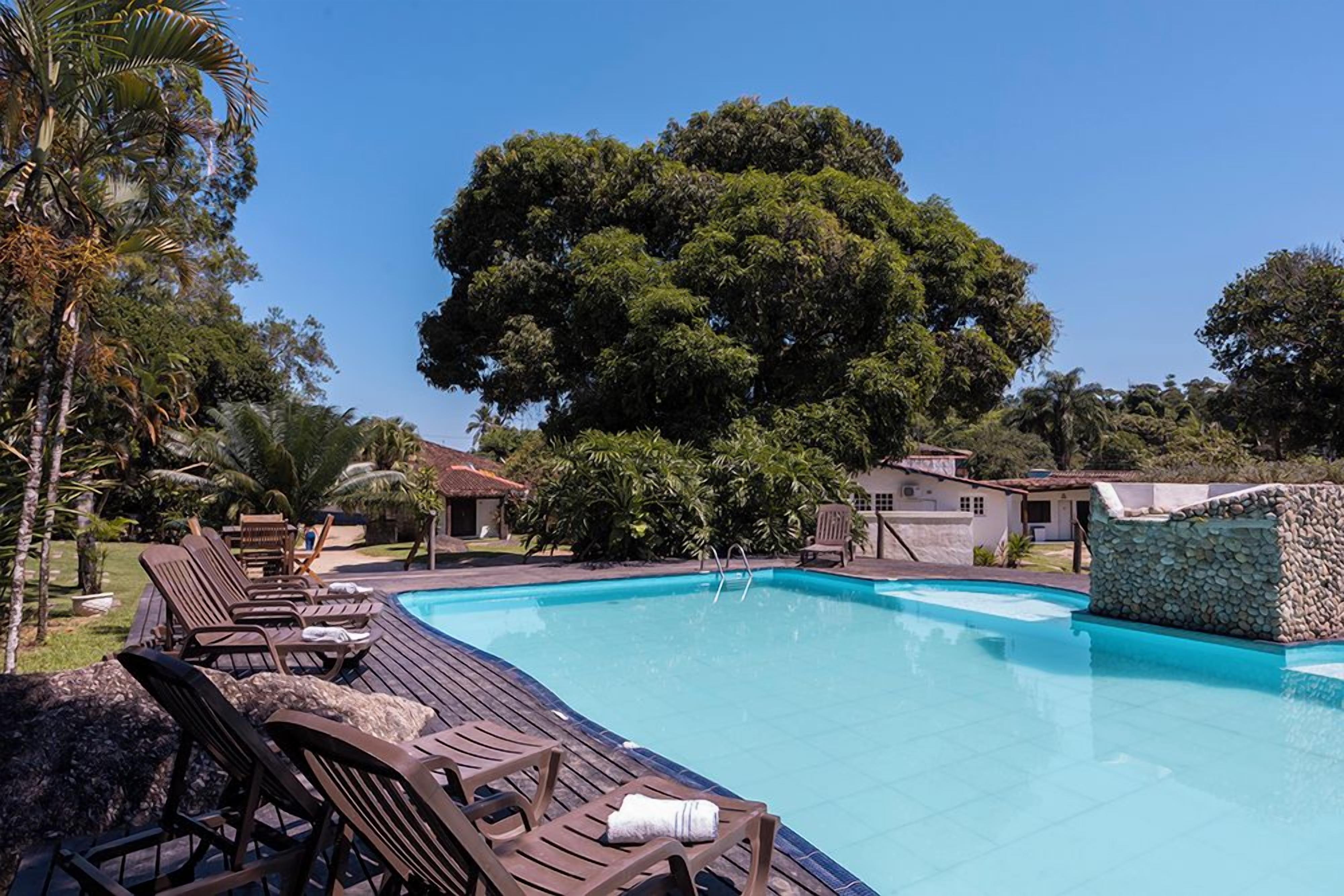 Piscina com espreguiçadeiras e muro de pedra.