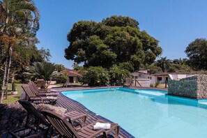 Une piscine avec des chaises longues et un mur en pierre.