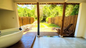 Een overdekt terras met een hottub, houten dek en een zitgedeelte buiten.