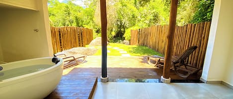 A covered patio with a hot tub, wooden deck, and outdoor seating area.