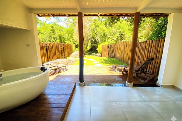 A covered patio with a hot tub, wooden deck, and outdoor seating area.