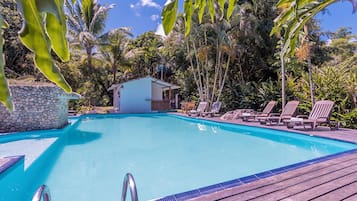 Una piscina al aire libre, sombrillas, sillones reclinables de piscina