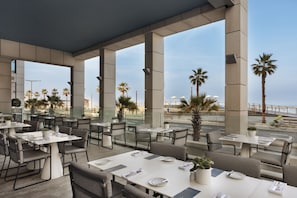 Enjoy dining in a spacious outdoor setting with comfortable seating and beautiful views of the beach and palm trees.