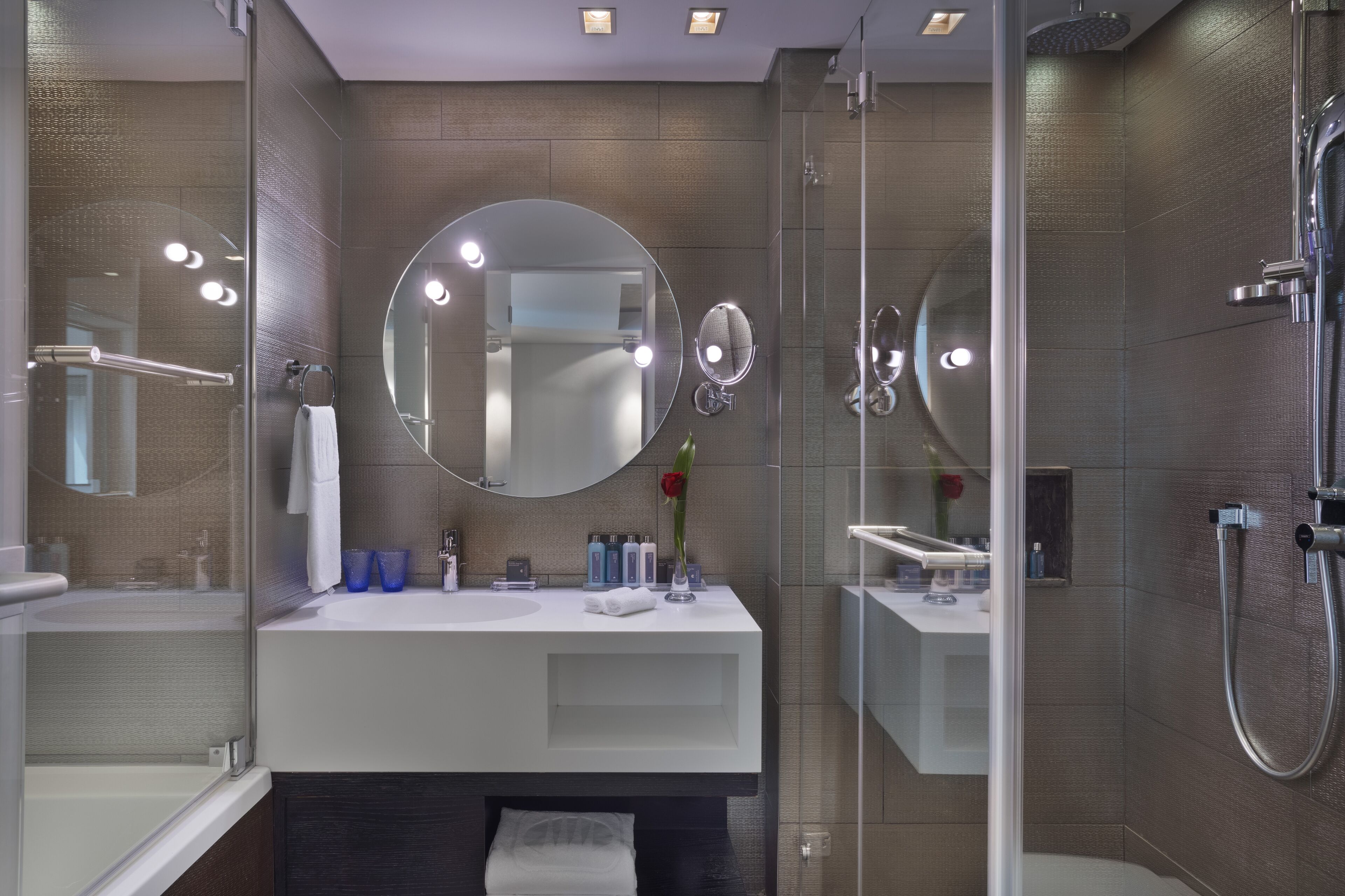 A modern bathroom with a glass-enclosed shower, a white vanity, and a large mirror.