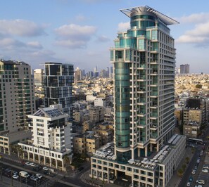 Experience the unique architecture of this high-rise building, featuring a curved glass facade and rooftop terrace with outdoor seating.