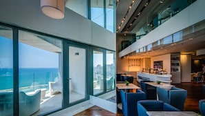 Un interior de hotel moderno con una zona de comedor, asientos y vistas al océano.
