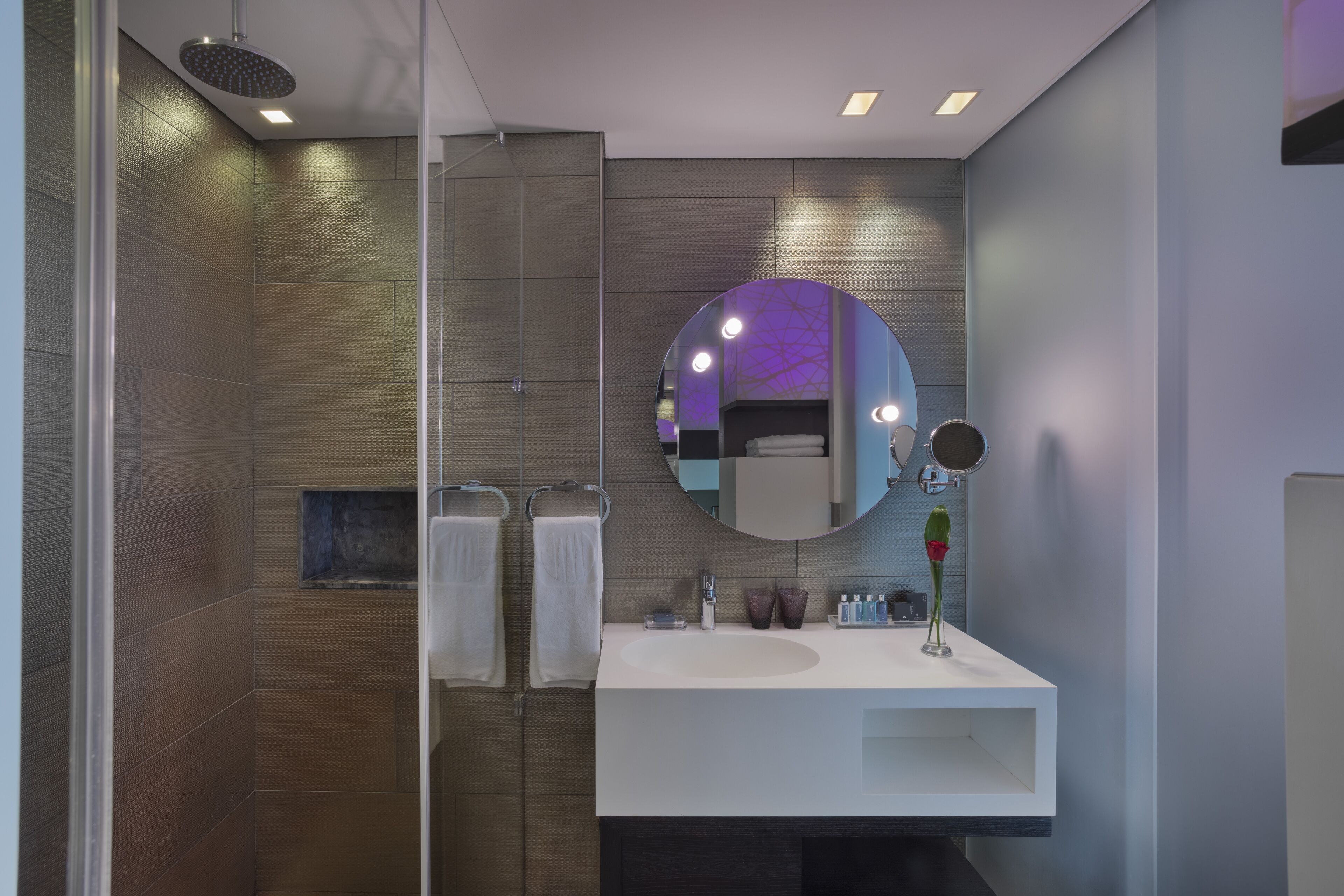 Un baño moderno con un espejo grande, un lavabo blanco y una zona de ducha.