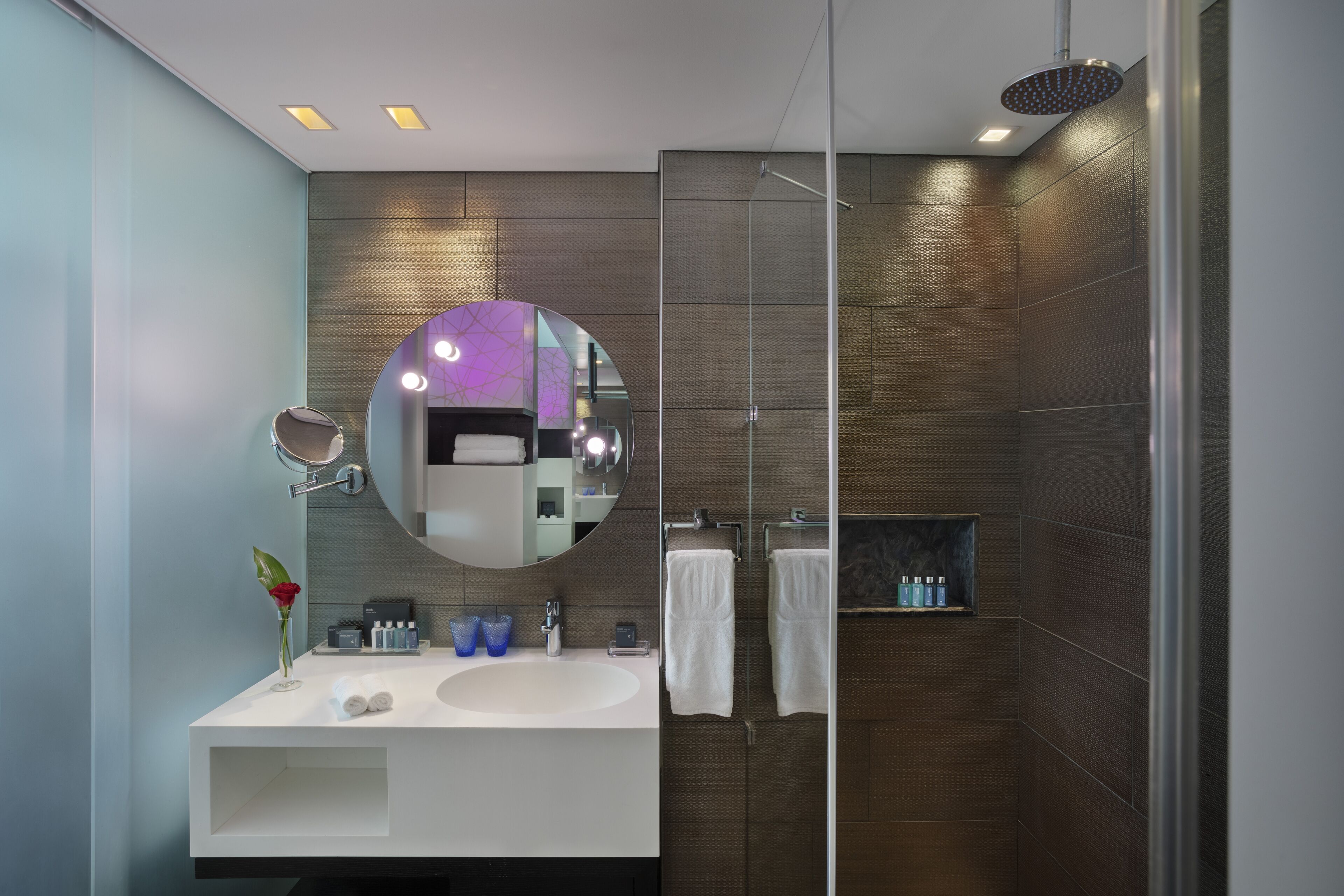 A modern bathroom with a large mirror, a sink, and a shower.