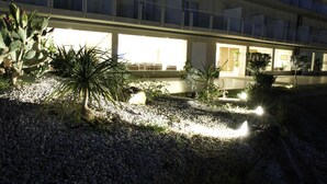 Un hotel de varios pisos, con iluminación exterior y diversas plantas.