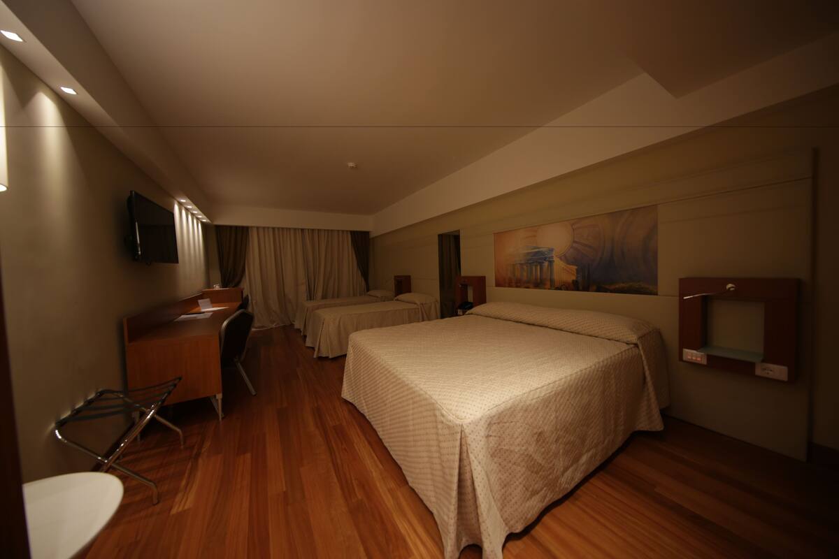 Una habitación de hotel con una cama grande, un escritorio, una silla y un televisor.