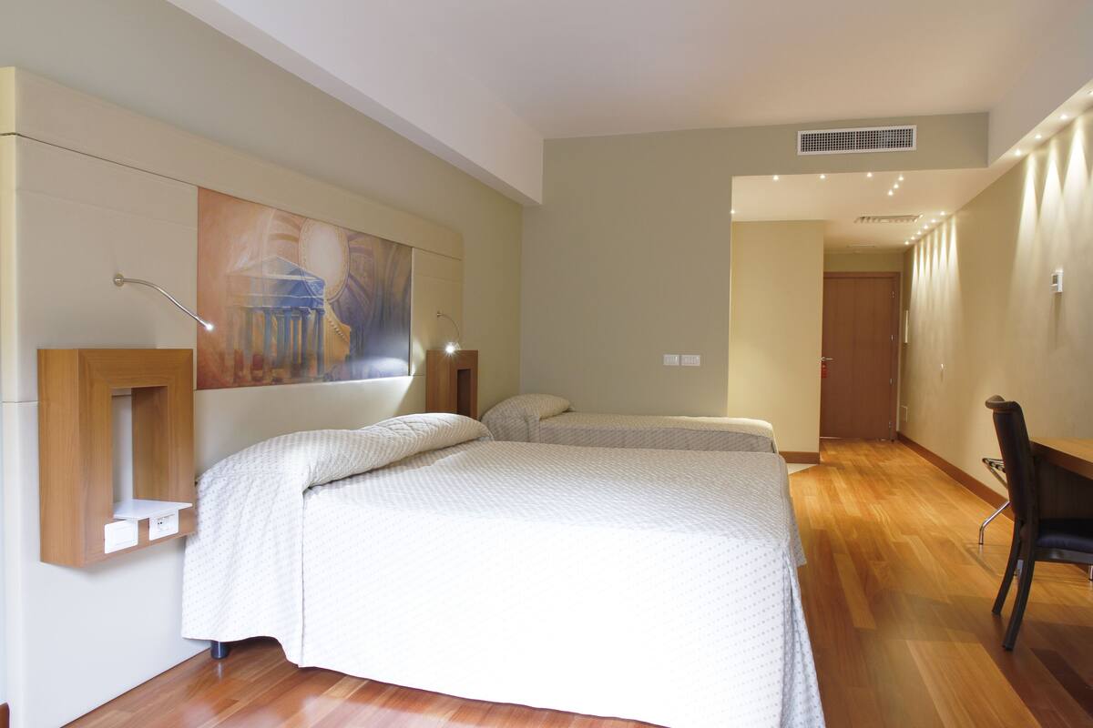 Una habitación de hotel moderna con una cama grande, un escritorio y una silla.