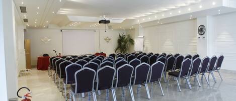A conference room with rows of chairs, a whiteboard, a projector, and a fire extinguisher.