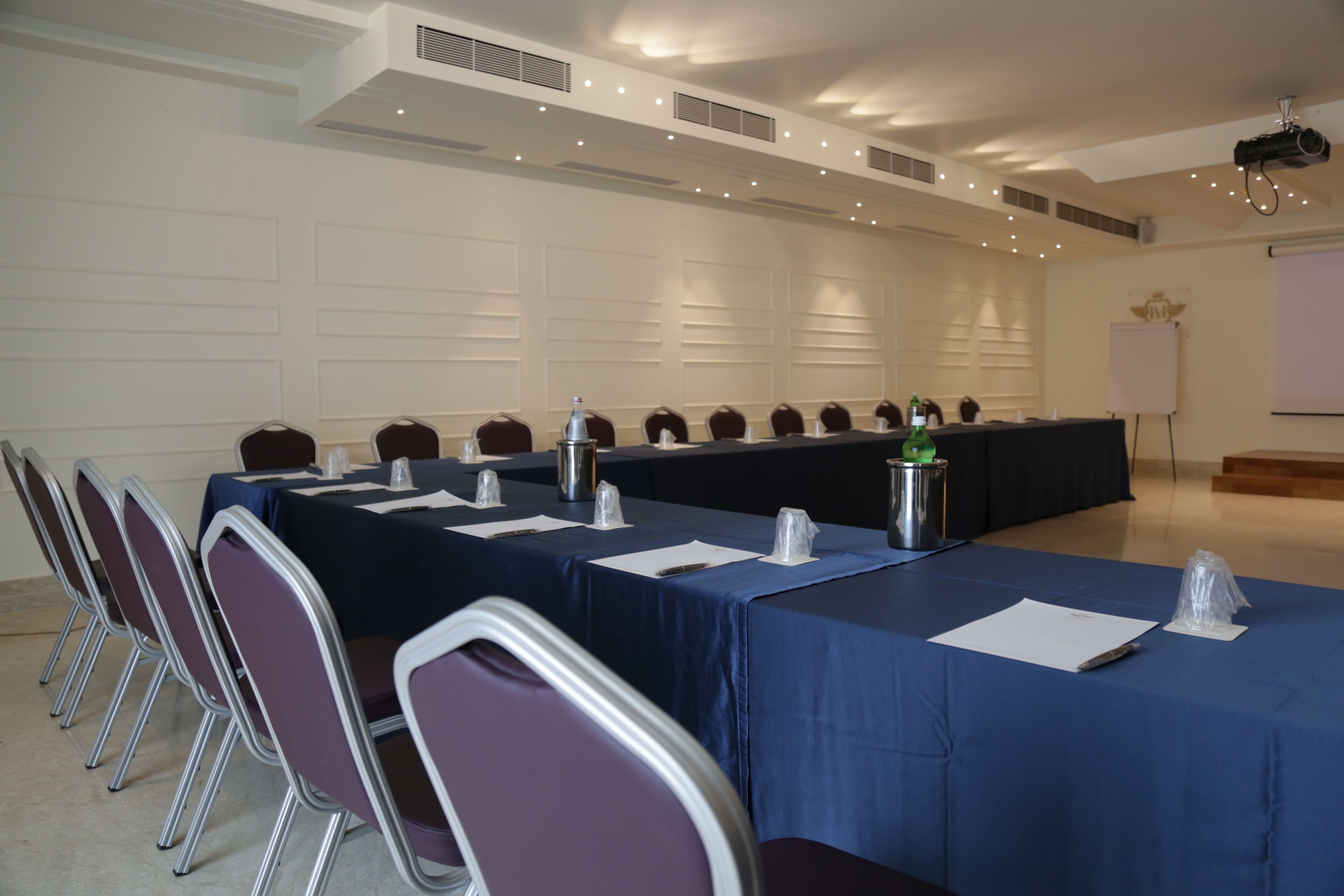 Une salle de conférence équipée d’une longue table, de chaises et d’un écran de projection.