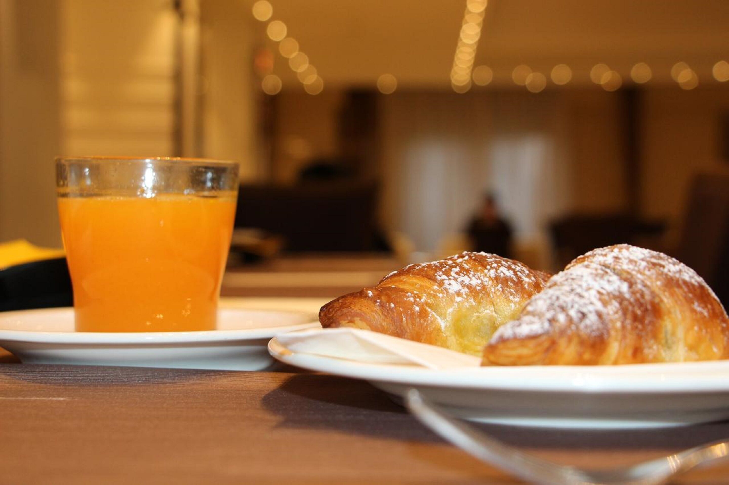 A breakfast setting with a glass of orange juice and a plate with a pastry.