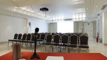 Una sala conferenze con file di sedie, un leggio, un proiettore e un estintore.