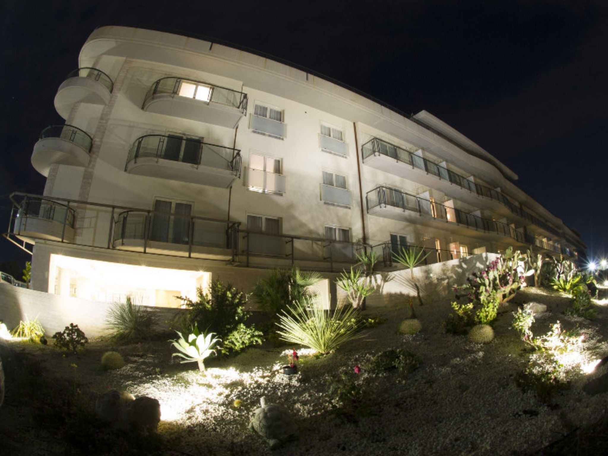 Ein mehrstöckiges Hotel mit Balkonen und einem angelegten Garten.