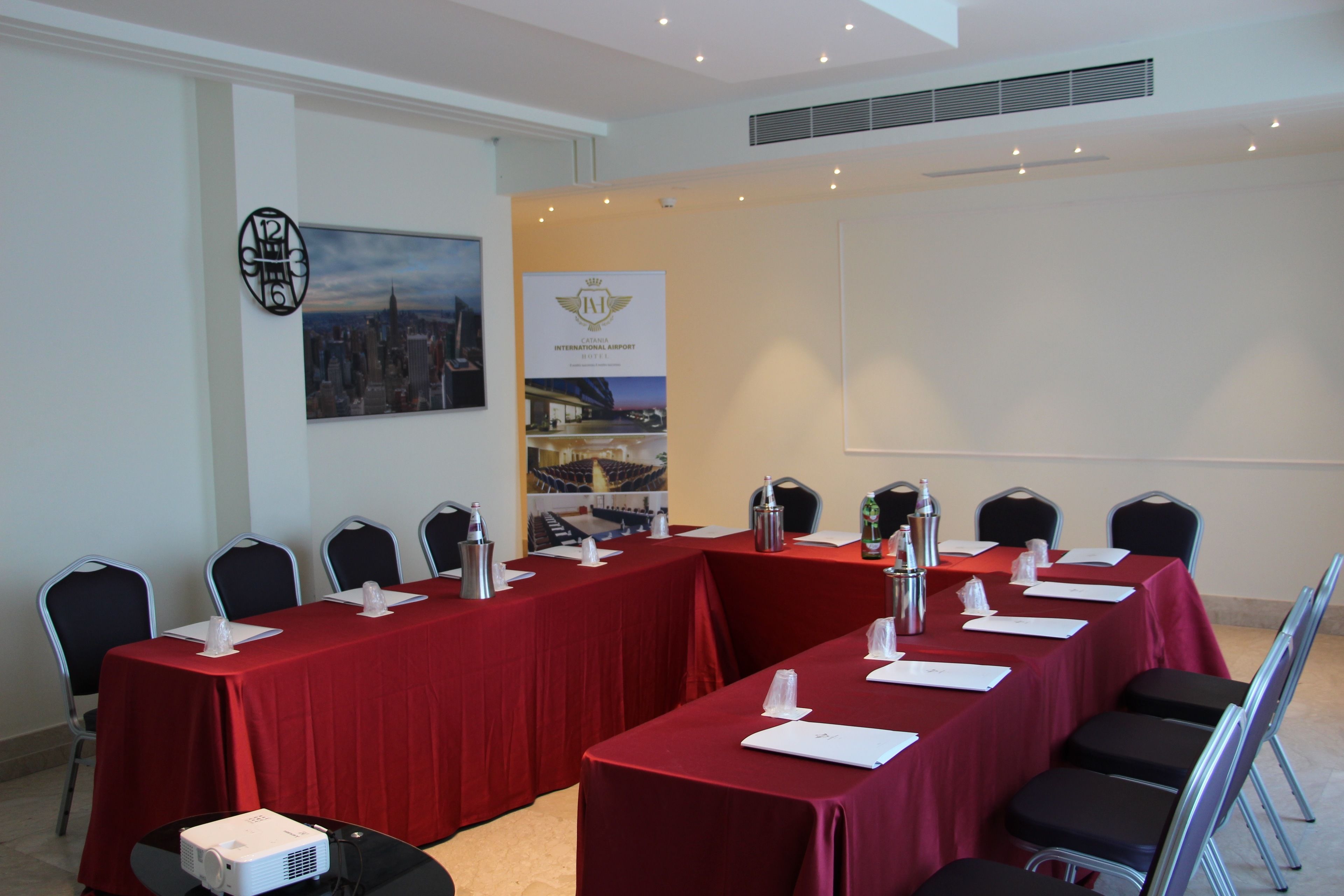 A conference room with a long table, chairs, a projector, and a banner.