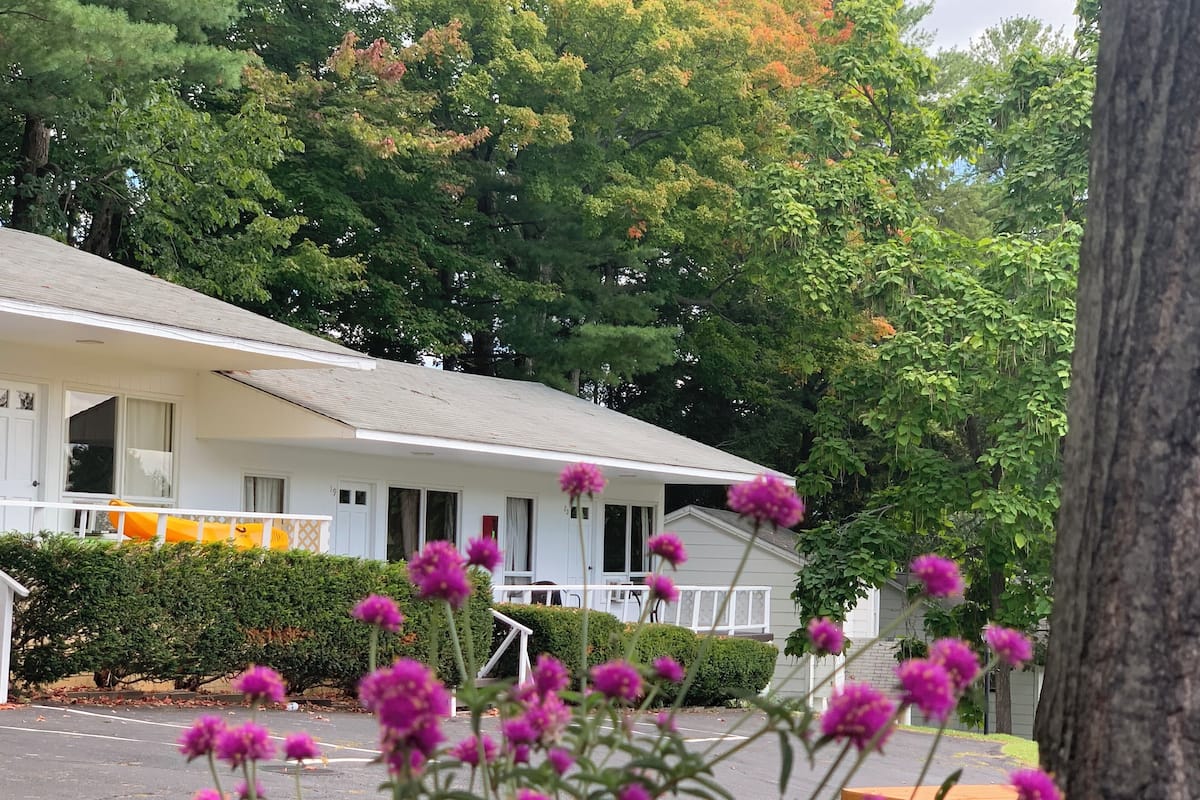 A white motel with a covered porch, a yellow inflatable pool, and a parking lot.